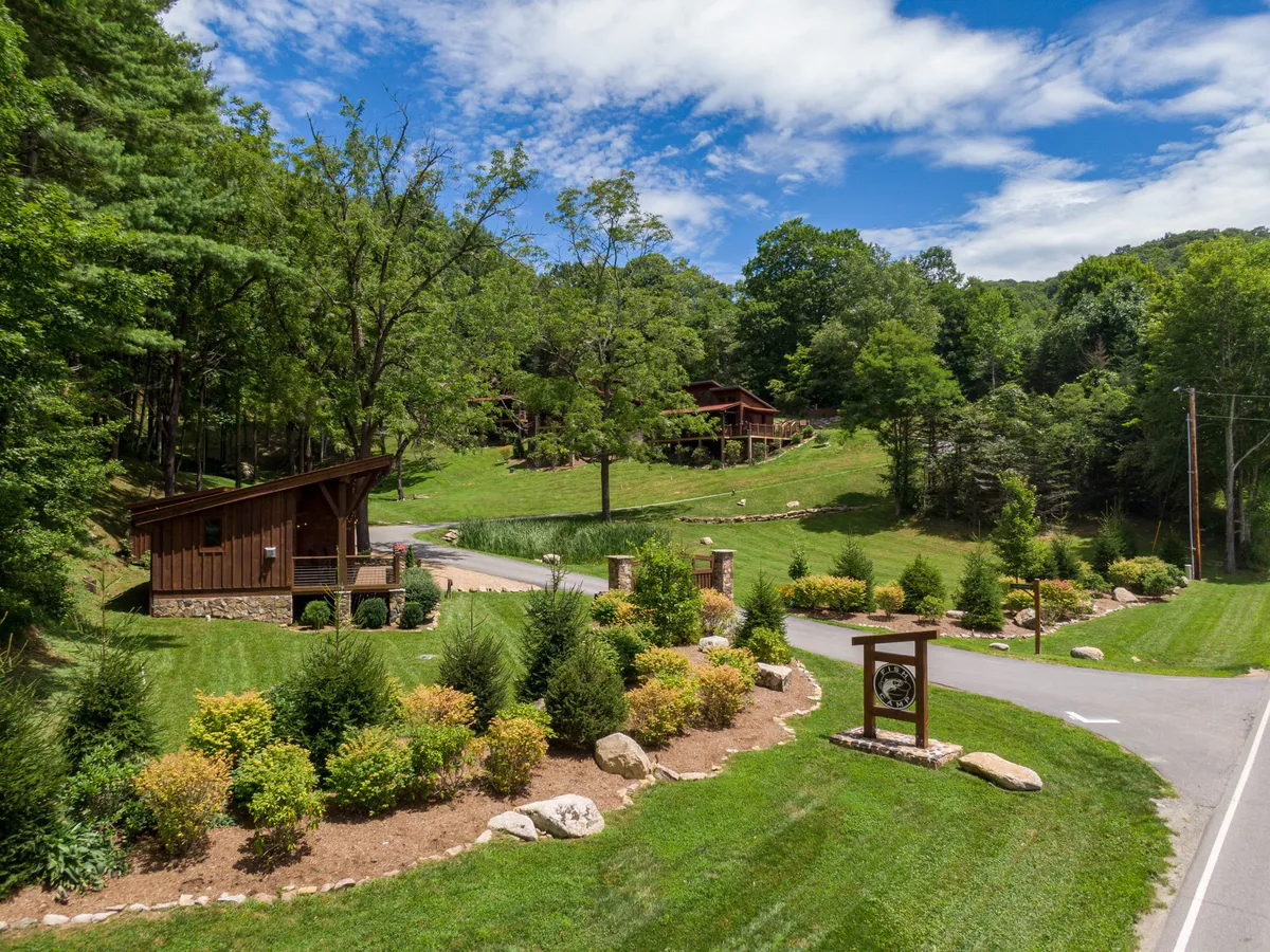 The cabin is framed by rich greenery, a pathway, and a signpost, suggesting easy access to walking trails and outdoor adventures. The serene atmosphere and visible path directly align with the section’s mention of woodland walks and community exploration with a pet.