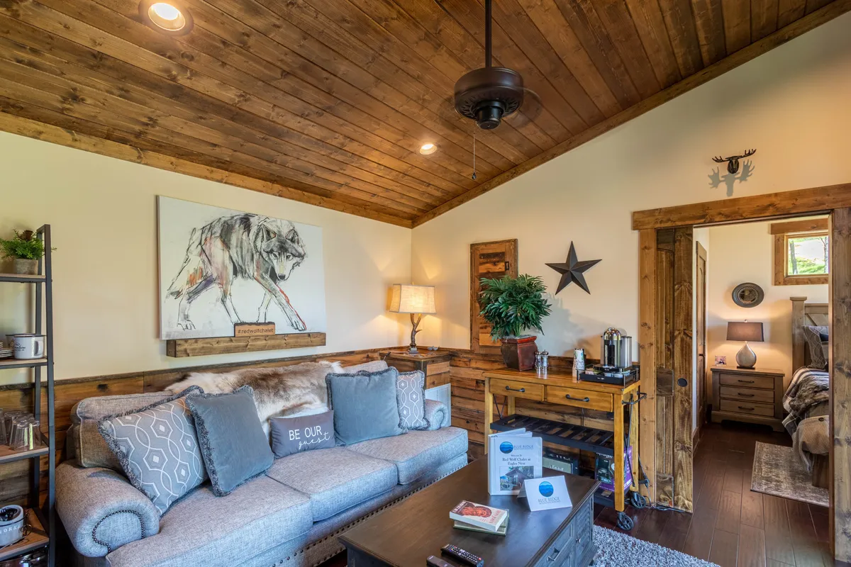 A close-up of a welcoming seating area with a plush sofa, wolf artwork on the wall, and a table with decorative accents, set in a softly lit environment ideal for relaxation and intimate conversation.