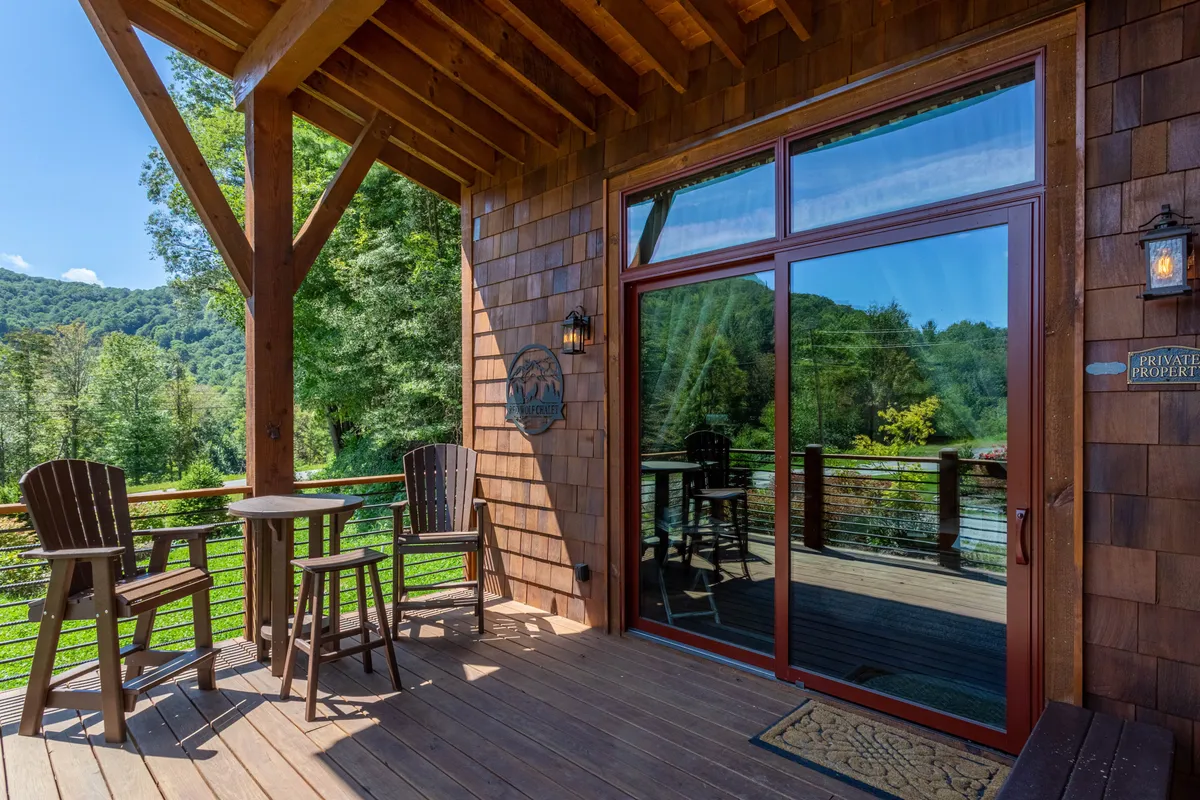 A cozy wooden deck furnished with comfortable seating, overlooking sweeping mountain views. The scene suggests tranquility and relaxation after a day of activity, with hints of sunrise or starlit evenings.